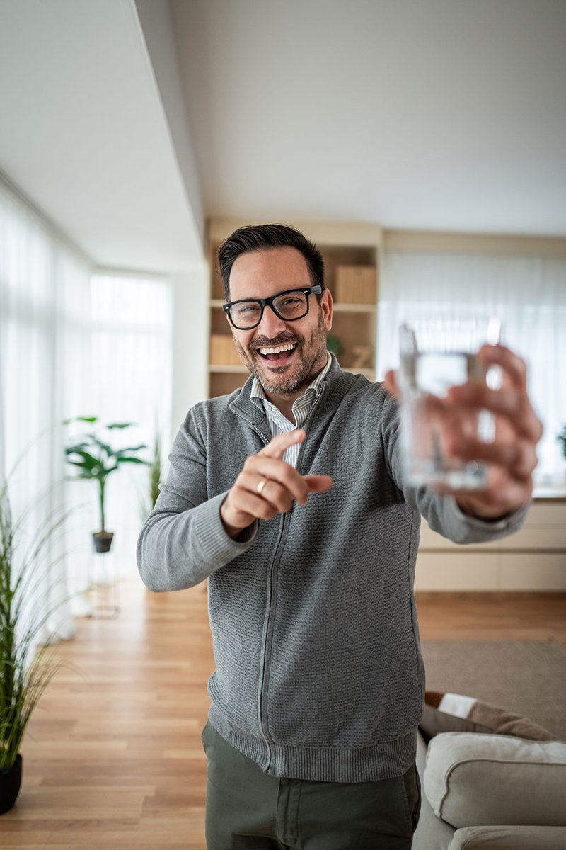 Happy homeowner enjoying clean filtered water at home